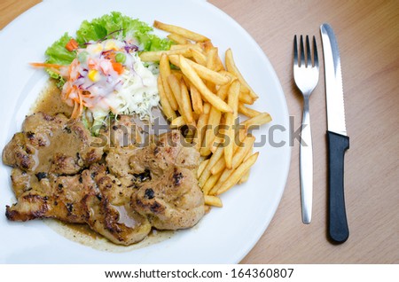Pork Steak, French fries and vegetables Salad with Fork and Knife