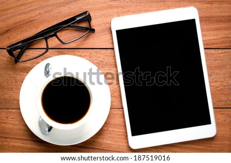 empty tablet and a cup of coffee on the wooden desk background