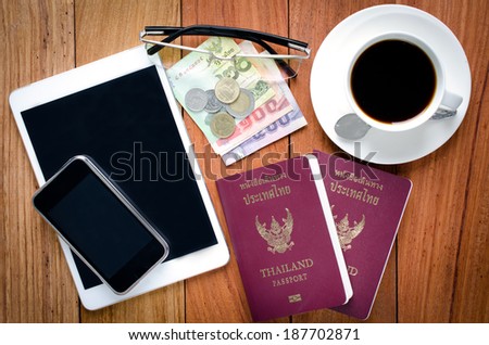 Thailand Passport with currency , Coffee and Cell Phone on a Wood Background.
