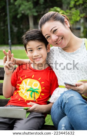 Asian woman  with your son showing victory sign in the park