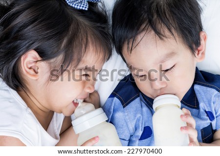 Closeup portrait of happy Asian little boy and girl  drink some mile from bottle on white background