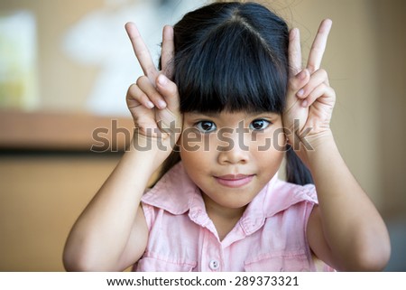Happy little Asian girl smile and making victory sign