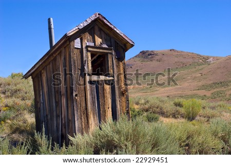 An old toilet or \'outhouse\' sitting in the middle of nowhere, evoking memories of the past