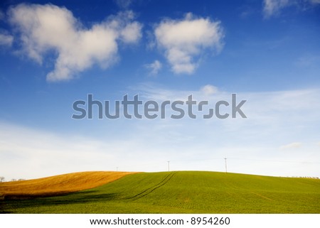 Farm land and fields set against a blue sky with white clouds