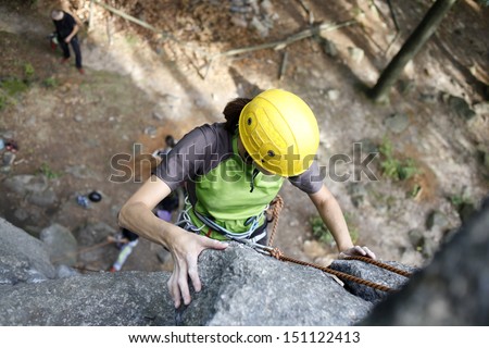 Young woman climbing on a limestone wall, rock climbing in mountains with natural background.