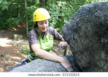 Image of pretty young woman climbing on a natural wall, rock climbing in mountains with natural background.
