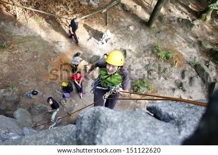 Image of pretty young woman climbing on a natural wall, rock climbing in mountains with natural background.