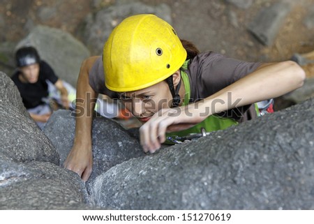 Young woman climbing on a wall, rock climbing in mountains with natural background.