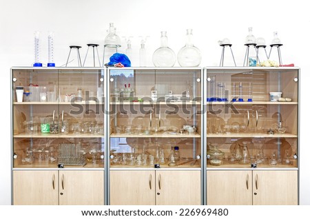 Different laboratory glassware and equipment on shelves.