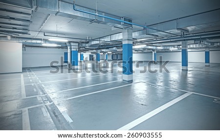 Cross processed photo of underground parking, industrial interior background.
