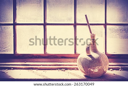 Vintage filtered rustic background, old vase on grungy window.