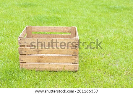 Empty wooden box on green grass, space for text.