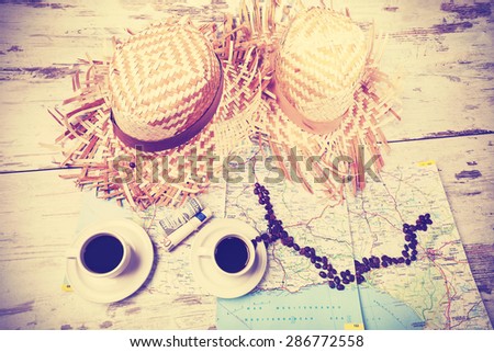 Vintage instagram stylized summer adventure concept with coffees, map; money and hats on wooden table.