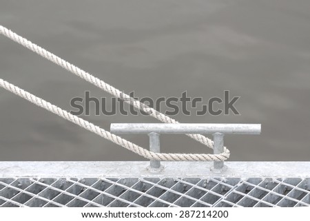 Marina bollard with rope, marine background with space for text.