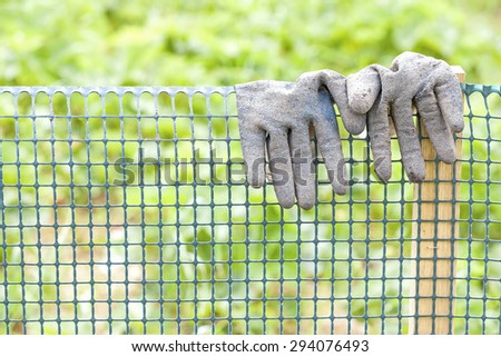 Dirty garden gloves on a plastic fence, gardening concept, shallow depth of field.