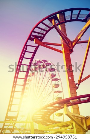 Vintage stylized roller coaster in amusement park at sunset.
