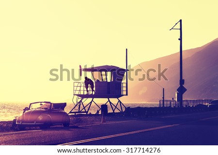Vintage filtered sunset over beach with lifeguard tower, Pacific Coast Highway, USA.