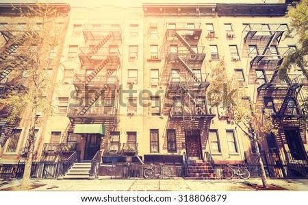 Old film retro style photo of New York building with fire escape ladders, USA.