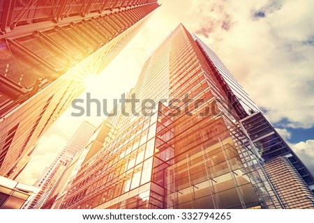 Vintage toned sunset over skyscrapers, modern business background with flare effect.