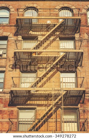 Retro style photo of New York building with fire escape ladders, USA.