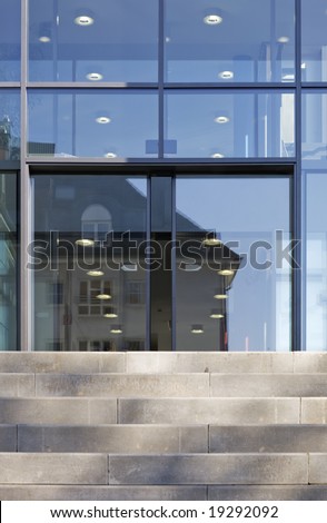 The front door of a office block, reflecting  buildings in the glass