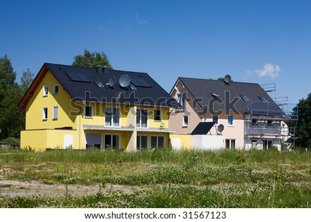 Two houses with solar panels and satellite dishes under construction
