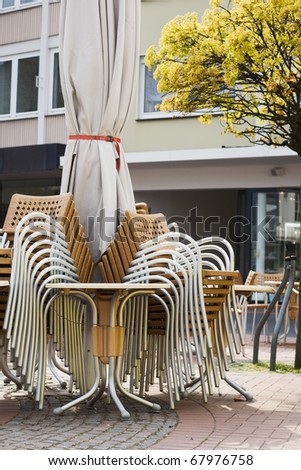 Stack of chairs, table and closed Parasol
