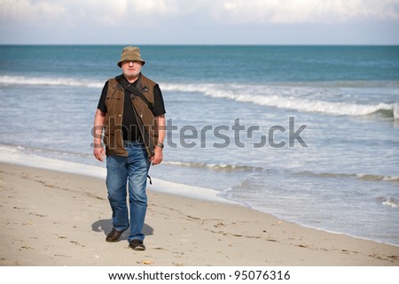 Senior man with backpack walking on the beach, island of Djerba, Tunisia, Africa