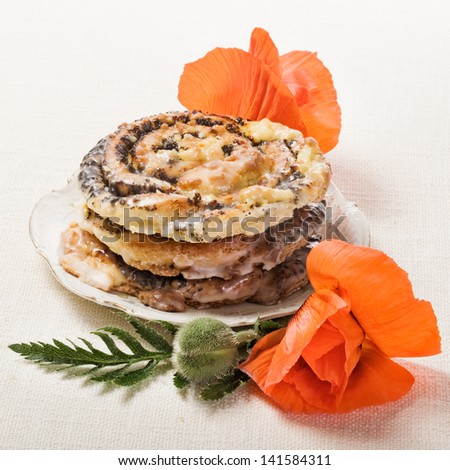 Poppy seed rolls, traditional german Mohnschnecke pastry, on plate with fresh poppy flowers