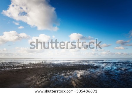 Mud flat at low tide. North sea landscape with cloud sky.  Nature reserve and travel destination in Germany