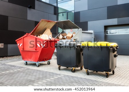 Red dumpster, recycle, waste and garbage bins near new office building. Backyard view