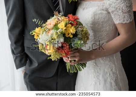 The bride and groom holding wedding bouquet of roses and love flower