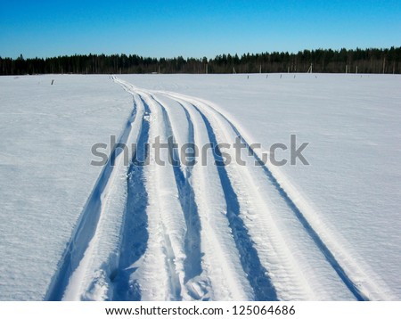 Snowy track.  Snowmobile trail from left in a snowy field
