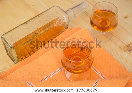 Glass and bottle of hard liquor like scotch, bourbon, whiskey or brandy on wood background with texture
