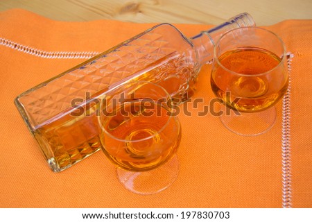 Glass and bottle of hard liquor like scotch, bourbon, whiskey or brandy on wood background with texture