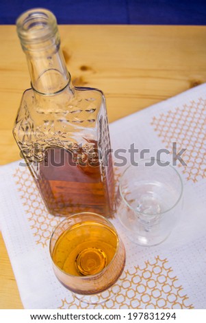 Glass and bottle of hard liquor like scotch, bourbon, whiskey or brandy on wood background and white texture