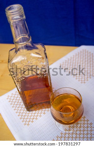Glass and bottle of hard liquor like scotch, bourbon, whiskey or brandy on wood background and white texture