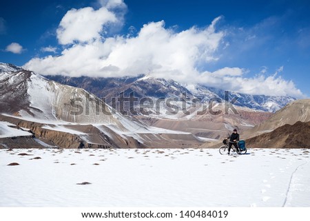 Man on bike rides in the snow in the high mountains of the Himalayas. Annapurna track Himalayas