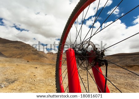 Red Wheel Mountain Bike. backdrop of the mountains , blue sky with clouds . Focus on the front wheel. Shallow depth of field