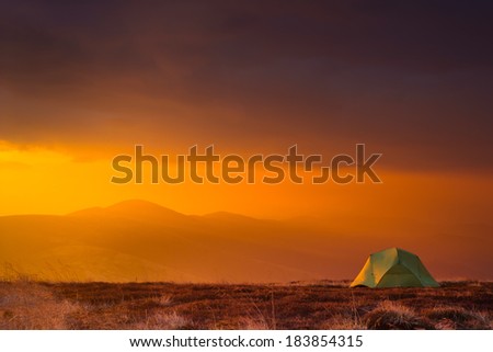 Majestic sunrise in the mountains landscape. Lonely tent on a mountain top. Overcast sky. Carpathian, Ukraine, Europe. Beauty world.
