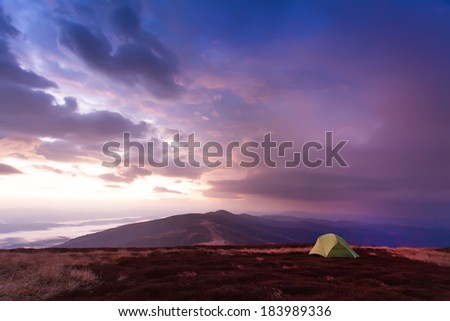 Majestic sunrise in the mountains landscape. Lonely tent on a mountain top. Overcast sky. Carpathian, Ukraine, Europe. Beauty world.