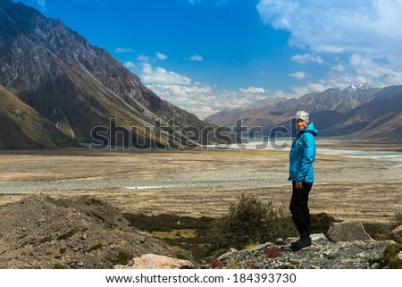 girl enjoying views of the snowy mountains Irek derived from the lake from Glentanner Park Centre near Mount Cook, on a background of blue sky with clouds, snowy Southern Alps in New Zealand.