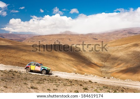 Colorful retro car rides through Dades canyons in Morocco in Atlas Mountains, Africa. Background blue sky with clouds. Beautiful World.