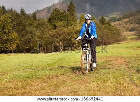 girl rides a bicycle in the countryside along the cows grazing in the meadow