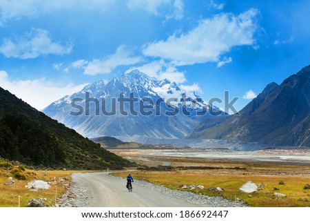 A mountain biker rides along a winding gravel track in a valleyNew Zealand, Southern Alps