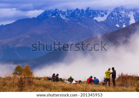 group of friends in hiking in high mountains. Admire the snow-capped peaks, fog. Beautiful world