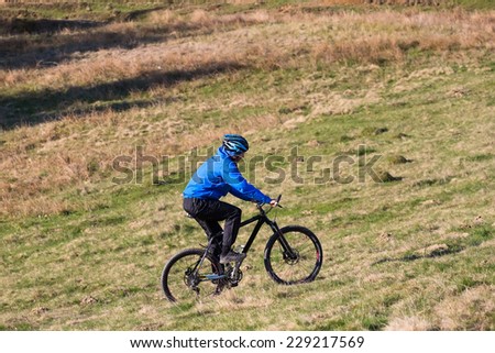mountain biker on sunny give rides on the rolling hills of green forest