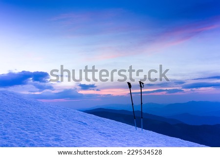 Colorful winter sunrise in mountains. Ski sticks or trekking poles.