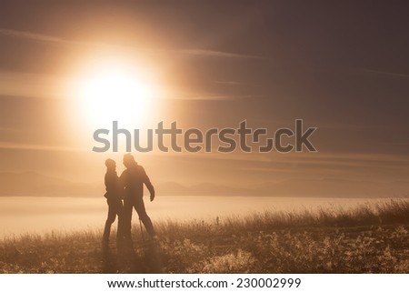 Silhouette active couple in love with Trekking pole in the morning fog. Landscape composition, background mountains and sunrise.