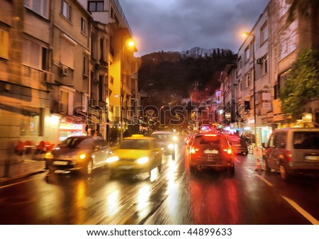night traffic in rainy city, shot from moving car, subjects blurred in motion